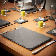 Set of slate placemats and slate coasters on a dining table