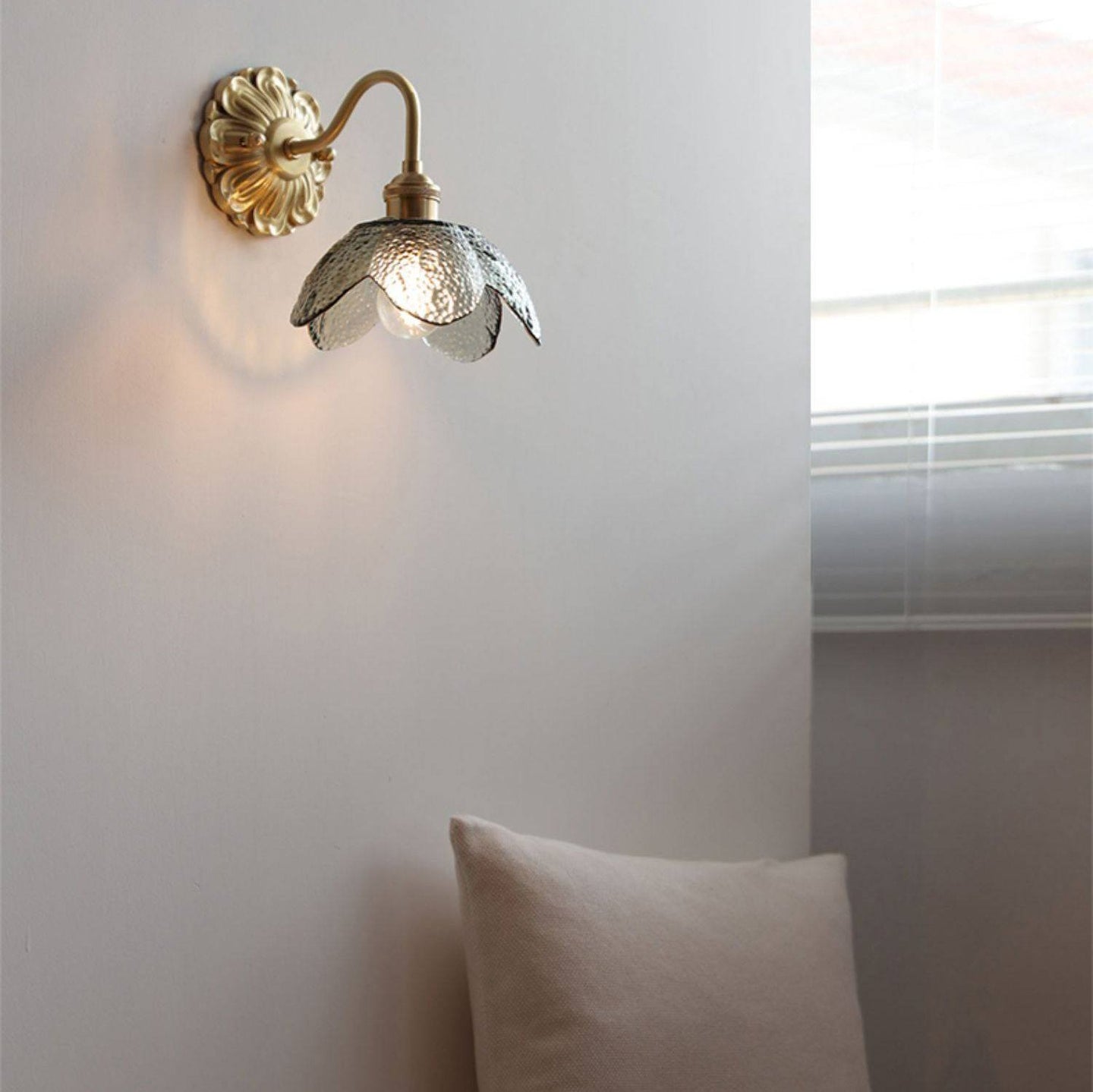 A sleek brushed brass wall light with modern design and decorative glass element